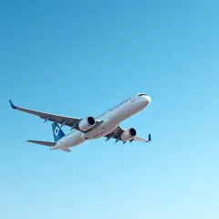 Biały samolot pasażerski leci na tle błękitnego nieba.