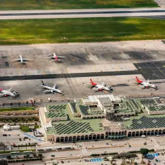 Lotnisko na Malcie, z samolotami Ryanair i Malta Air na płycie. Widok z lotu ptaka ukazuje ruchliwy terminal i pasy startowe.