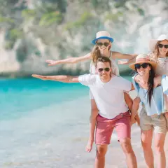 Rodzina na plaży, zastanawiająca się, ile kosztuje ubezpieczenie na wyjazd za granicę.
