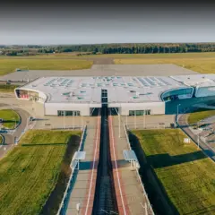 Nowoczesny terminal lotniska w Lublinie, otoczony polami i parkingami.