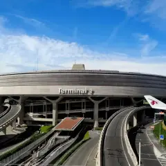 Terminal 1 na lotniskach w Paryżu, z charakterystyczną, okrągłą bryłą i wijącymi się drogami dojazdowymi.