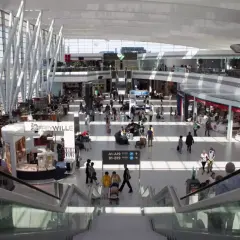 Tętniący życiem terminal lotniska w Budapeszcie. Ludzie spacerują, robią zakupy i czekają na loty wśród nowoczesnej architektury i sklepów.