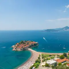 Sveti Stefan, Czarnogóra, to malownicza wyspa z czerwonymi dachami, połączona z lądem piaszczystą plażą. Czy Czarnogóra jest bezpieczna? Tak, to spokojne miejsce na wakacje.