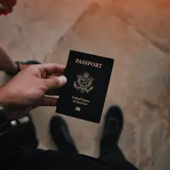 Dłoń trzyma czarny paszport USA. Czas na złożenie wniosku o paszport i rozpoczęcie podróży.