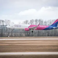 Samolot Wizz Air z różowym ogonem ląduje na pasie startowym. Wizz rozkład miejsc w samolocie Wizzair jest dobrze widoczny.