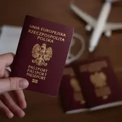 Dłoń trzyma polski paszport. Obok leżą inne dokumenty, maseczka i samolot. Zastanawiasz się, ile się czeka na paszport?