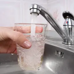 Ręka trzyma szklankę pod kranem, nalewając wodę. Czy w Grecji można pić wodę z kranu? To pytanie nurtuje wielu turystów.