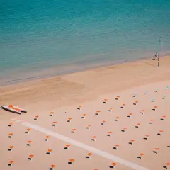 Pusta plaża w Rimini z rzędem parasoli i łodzią ratunkową.