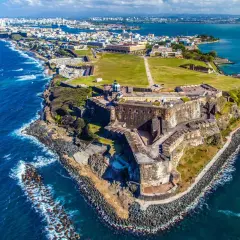 Widok na zabytkową fortecę i miasto San Juan, gdzie jest Puerto Rico. Błękitne morze otacza skaliste wybrzeże.