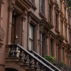 Eleganckie kamienice w brązie, typowe dla **Harlem, Nowy Jork**, z ozdobnymi gzymsami i kutymi balustradami schodów.