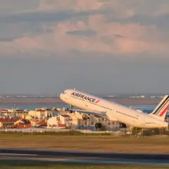 Samolot Air France startuje z pasa startowego na tle miasta i morza.