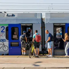 Ludzie z rowerami wsiadają do pociągu, szukając tanich biletów Intercity na wakacyjną podróż.