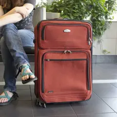 Osoba z paszportem czeka na lotnisku z walizką. Czy Kenia jest bezpieczna na podróż?