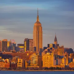 Zachód słońca nad Manhattanem, z Empire State Building i Chrysler Building w tle. Zastanawiasz się, ile się leci do Nowego Jorku?