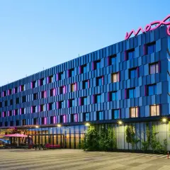 Nowoczesny hotel Moxy Hotels Pyrzowice z neonowym logo na dachu i kolorowymi podświetleniami okien.