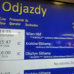 Tablica odjazdów pociągów pokazuje, jak sprawdzić opóźnienie pociągu. Widać opóźnione pociągi do Wiednia, Krakowa i Olsztyna.