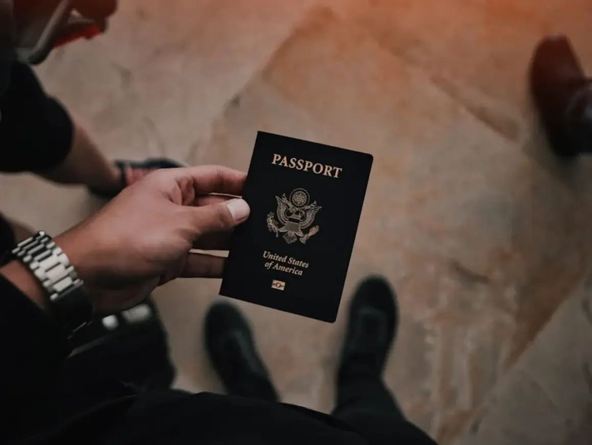 Dłoń trzyma czarny paszport USA. Czas na złożenie wniosku o paszport i rozpoczęcie podróży.