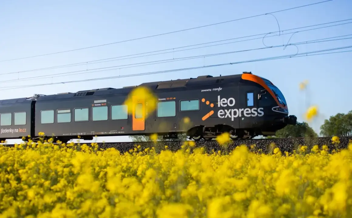 Czarny pociąg express Leo Express mija pole kwitnącego rzepaku.