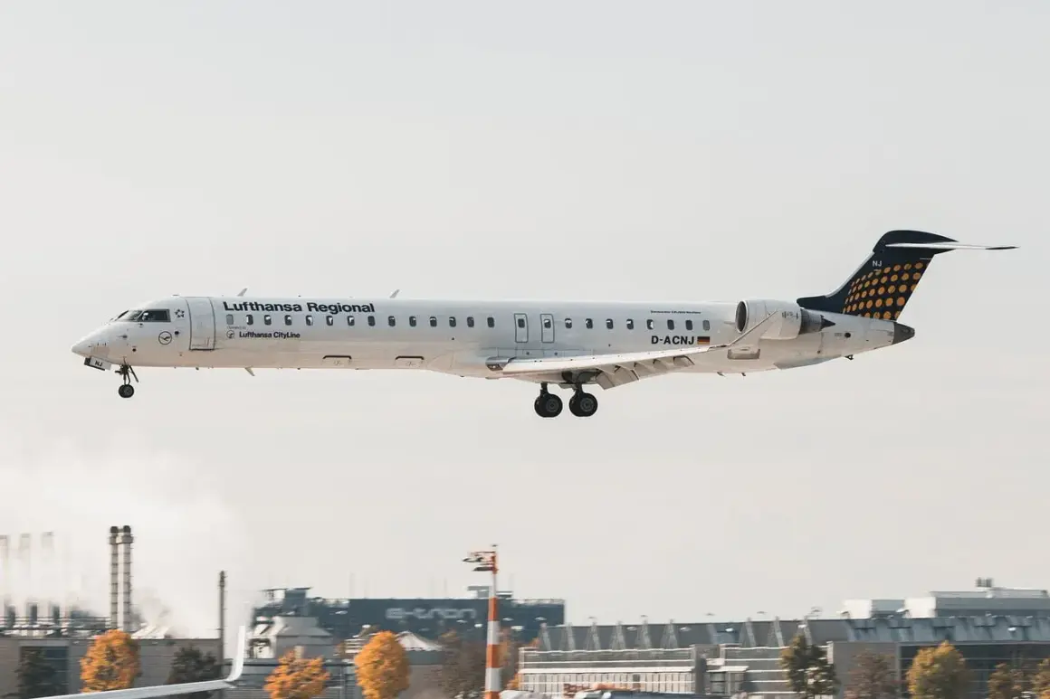 Samolot Lufthansa Regional z podwoziem wysuniętym do lądowania, leci nisko nad lotniskiem.
