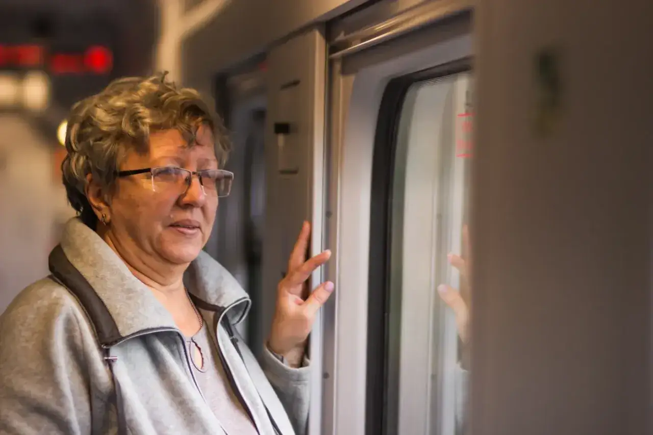 Starsza pani w okularach podróżuje pociągiem PKP, ciesząc się zniżkami.