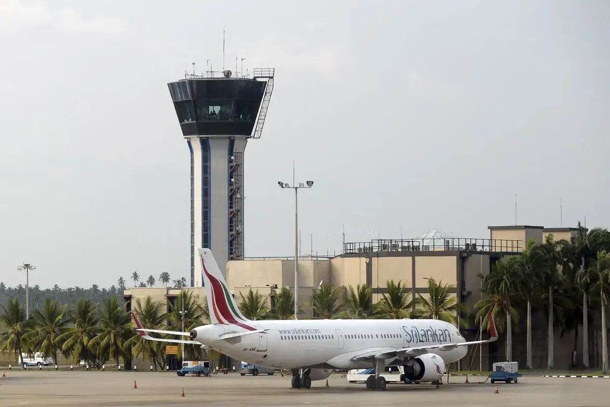 Samolot SriLankan Airlines na lotnisku, w tle wieża kontroli lotów i palmy. Planujesz sri lanka loty?