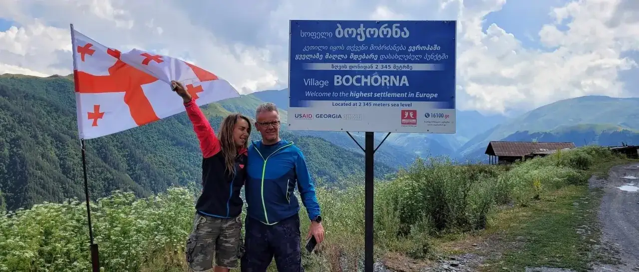 Para, z gruzińską flagą, na tle gór i znaku 