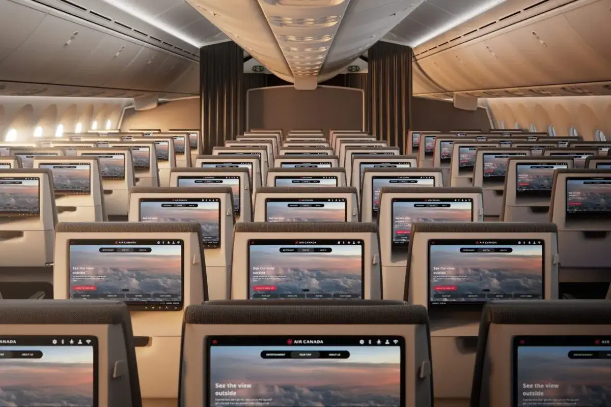 Wnętrze samolotu Boeing 787-10 Air Canada. Rzędy ekranów pokładowych wyświetlają widok chmur.