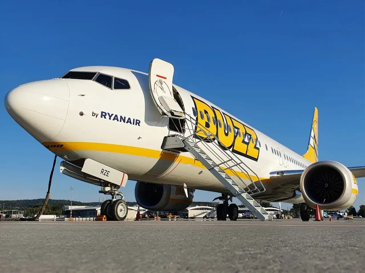 Samolot Buzz, należący do Ryanair, lśni w słońcu na płycie lotniska.