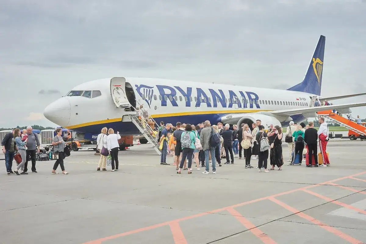 Pasażerowie wsiadają do samolotu Ryanair. Od ilu lat można latać samemu? Zazwyczaj od 16 roku życia, ale warto sprawdzić regulamin przewoźnika.
