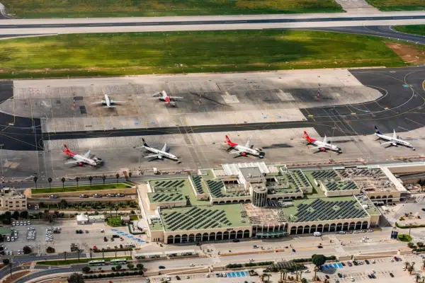 Lotnisko na Malcie, z samolotami Ryanair i Malta Air na płycie. Widok z lotu ptaka ukazuje ruchliwy terminal i pasy startowe.
