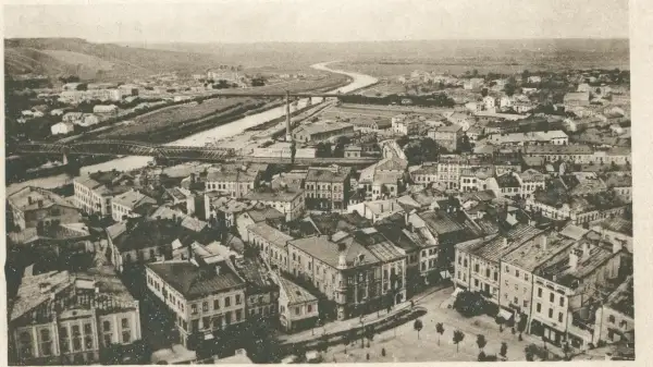 Widok z lotu ptaka na miasto z rzeką i mostami. Widać gęstą zabudowę, fabryki i wzgórza w tle. Warto przemyśl zasanie tego miejsca.