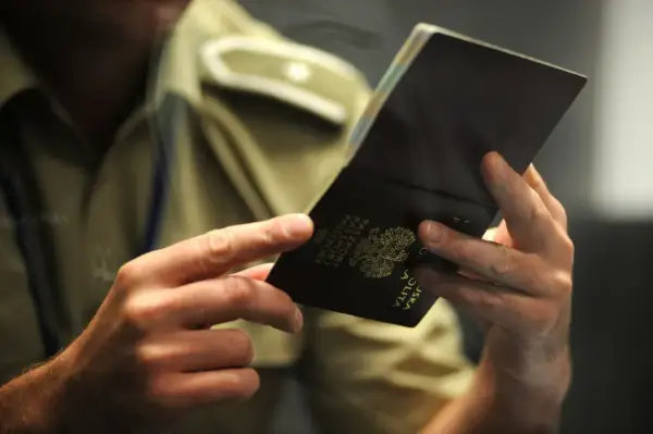 Dłonie trzymają otwarty polski paszport. Czy trzeba oddać stary paszport? Urzędnik sprawdza dokument.
