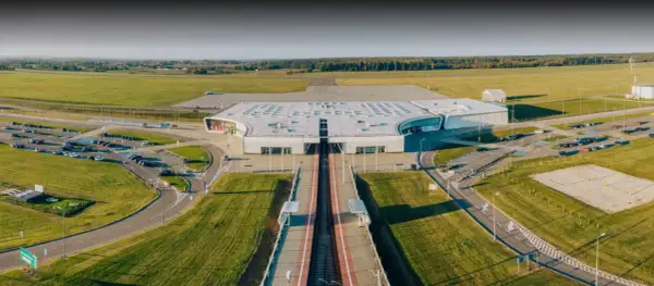 Nowoczesny terminal lotniska w Lublinie, otoczony polami i parkingami.
