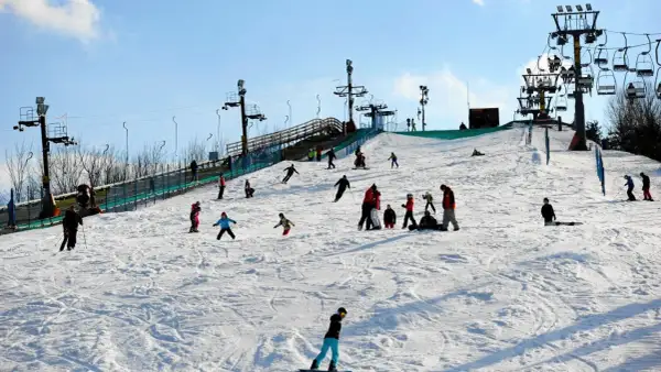 Zimowe atrakcje dla dzieci na Mazowszu: stok narciarski z wyciągiem, na którym bawią się rodziny, ucząc się jeździć na nartach i snowboardzie.