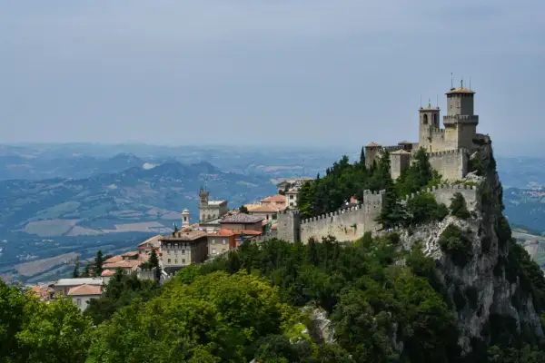 San Marino na terytorium Włoch, z górującymi wieżami i kamiennymi murami, wznosi się dumnie na skalistym szczycie, otoczone zielonymi wzgórzami.