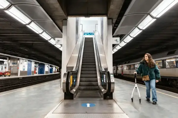 Kobieta z chodzikiem na peronie kolejowym, gotowa na podróże koleją.