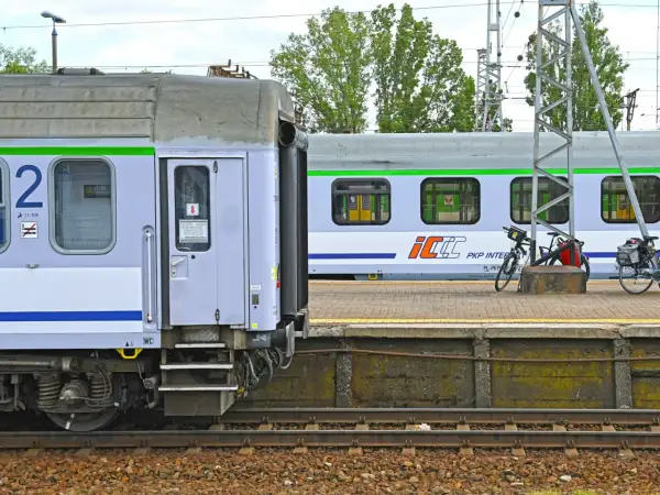 Nowe wagony PKP Intercity z zielonym pasem czekają na pasażerów. Na peronie stoją rowery.