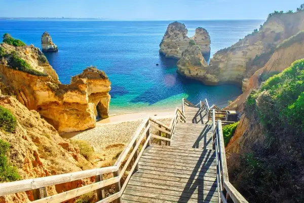 Malownicze klify i turkusowe morze w Portugalii. Schody prowadzą na ukrytą plażę, idealną na odkrywanie ciekawostki o Portugalii.