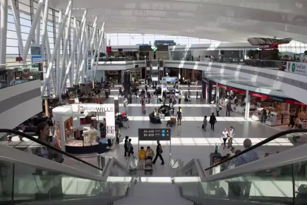 Tętniący życiem terminal lotniska w Budapeszcie. Ludzie spacerują, robią zakupy i czekają na loty wśród nowoczesnej architektury i sklepów.