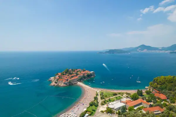 Sveti Stefan, Czarnogóra, to malownicza wyspa z czerwonymi dachami, połączona z lądem piaszczystą plażą. Czy Czarnogóra jest bezpieczna? Tak, to spokojne miejsce na wakacje.