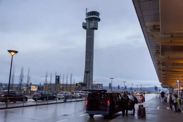 Wieża kontrolna na oslo lotnisko. Samochody i ludzie przy terminalu w deszczowy dzień.