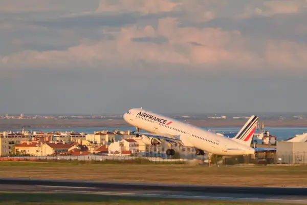 Samolot Air France startuje z pasa startowego na tle miasta i morza.