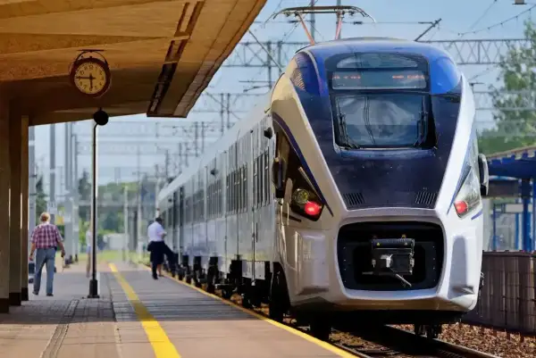 Pociąg Intercity na peronie. Zastanawiasz się, czy można jechać wcześniejszym pociągiem Intercity? Zegar na stacji pokazuje czas.