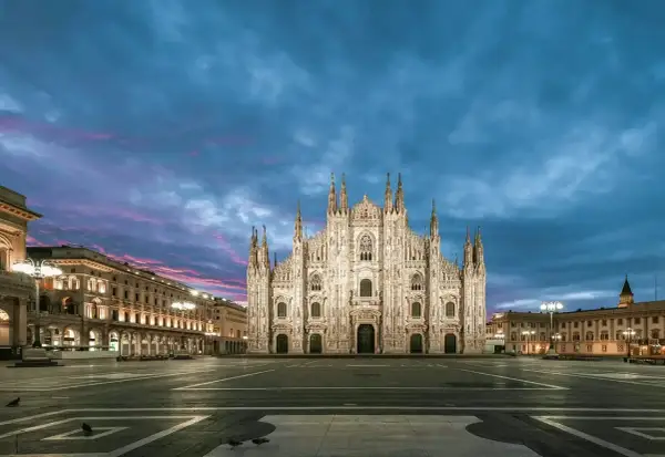 Majestatyczna katedra Duomo w Mediolanie nocą, oświetlona pod purpurowo-niebieskim niebem.