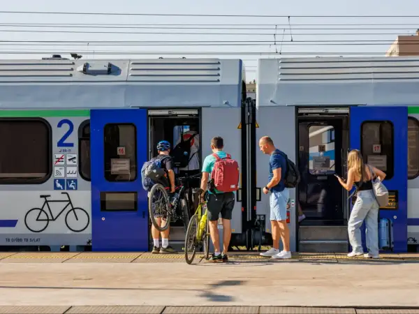 Ludzie z rowerami wsiadają do pociągu, szukając tanich biletów Intercity na wakacyjną podróż.