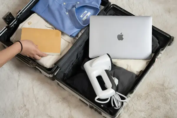 Pakowanie bagażu rejestrowanego: laptop, koszula, książka i podręczny parownica.