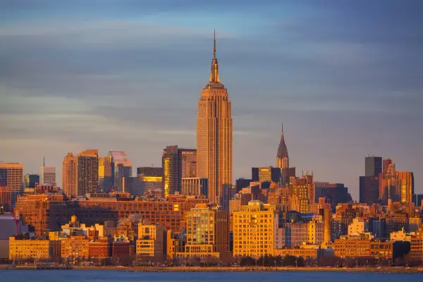 Zachód słońca nad Manhattanem, z Empire State Building i Chrysler Building w tle. Zastanawiasz się, ile się leci do Nowego Jorku?