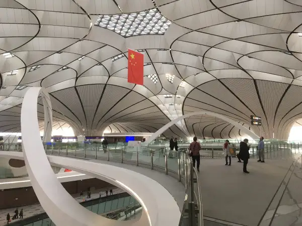 Nowoczesne lotniska w Chinach zachwycają architekturą. Wnętrze terminalu z flagą Chin i futurystycznym dachem.